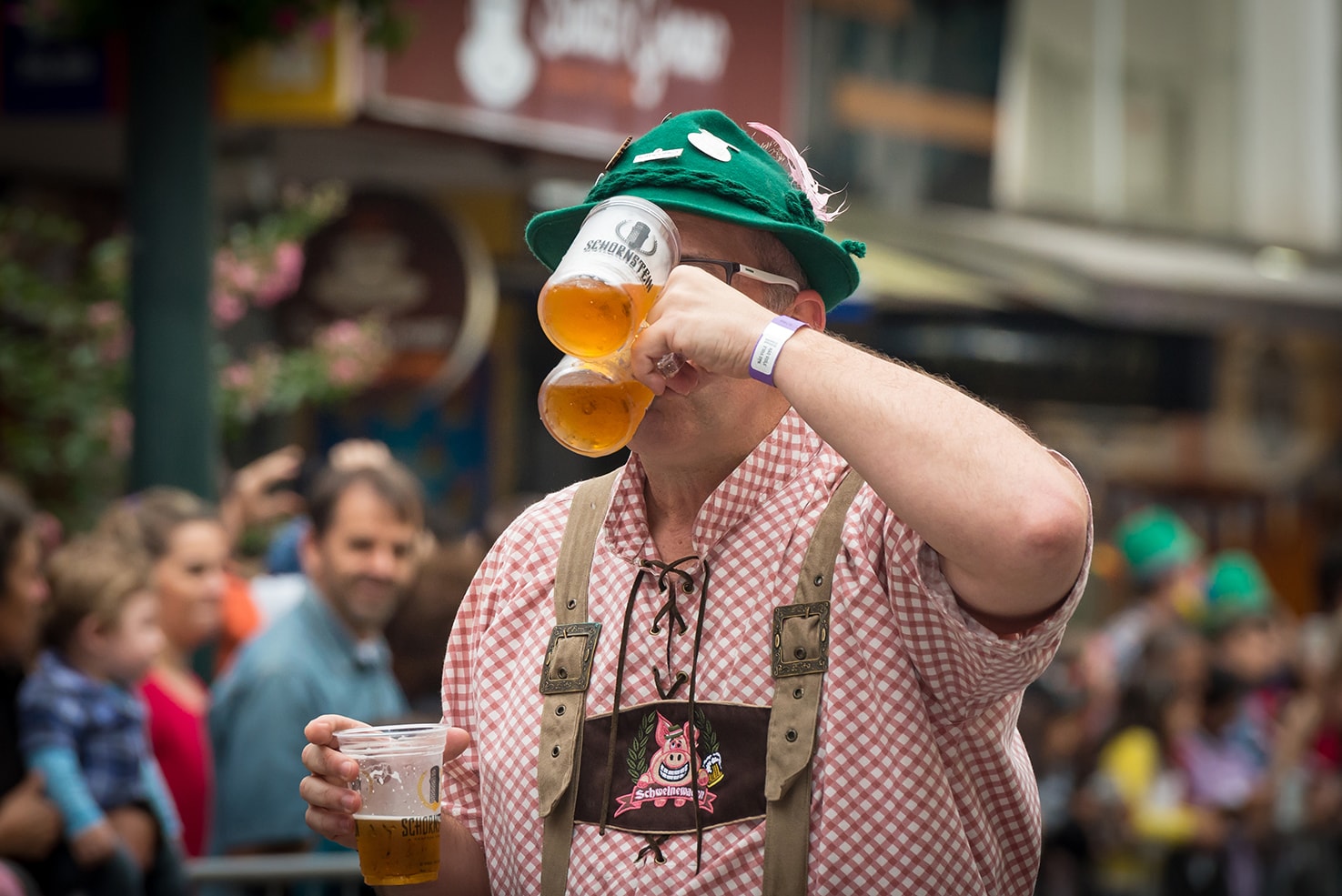Blumenau, Santa Catarina, Brazil - October 17, 2015: A close-up of a man dressed in German costume drinking three glasses of beer on the street parade in the heart of Blumenau celebrating the Oktoberfest.